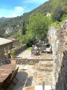 une terrasse en pierre avec une table et des bancs en bois dans l'établissement Les Terrasses, à Cabrespine