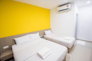 two beds in a room with a yellow wall at HomeStay 21 Hotel in Johor Bahru