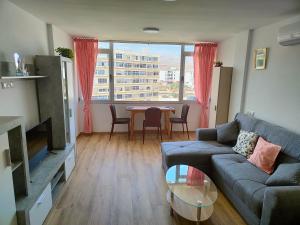 a living room with a couch and a table at Residencial Los Molinos con piscina, TV internacional y Wifi in Playa del Ingles