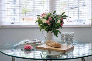a glass table with a vase of flowers and a pastry at Ipswich Town Centre - Apartment 7 in Ipswich