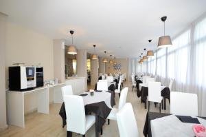 a dining room with white tables and white chairs at Hotel Airone in Marina di Pietrasanta