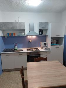 eine Küche mit einem Tisch und einem Herd Top-Backofen in der Unterkunft APARTMAN VERA in Cres