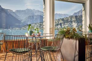 einen Tisch und Stühle mit Blick auf das Wasser in der Unterkunft Hotel Paradiso Conca d'Oro in Nago-Torbole
