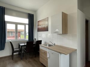 a kitchen with a sink and a table with chairs at Pisztráng17 Apartman in Gárdony