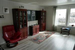 sala de estar con silla roja y algunos armarios en Seafront Holiday Home close to Reine, Lofoten en Sund