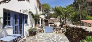 una casa blanca con un banco junto a una pared de piedra en Casa Ribeira en Coentral das Barreiras