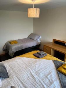 a bedroom with two beds and a desk and a lamp at 2 Bedroom house overlooking Pierowall Bay, Westray in Pierowall