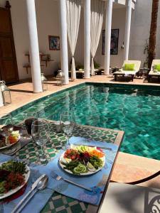 a table with plates of food next to a swimming pool at Riad Chergui in Marrakech
