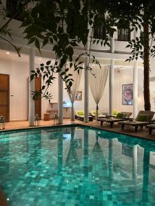 una piscina en un hotel con sillas y patio en Riad Chergui, en Marrakech