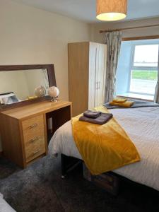 a bedroom with a bed and a dresser and a mirror at 2 Bedroom house overlooking Pierowall Bay, Westray in Pierowall