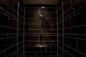 a bathroom with a shower with black tiles at Royal Amsterdam Hotel in Amsterdam