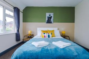 ein Schlafzimmer mit einem blauen Bett mit zwei Handtüchern darauf in der Unterkunft 5 Bedroom House By NYOS PROPERTIES Short Lets & Serviced Accommodation Manchester With Free WiFi in Birmingham