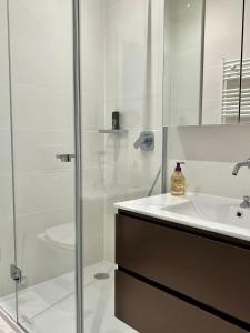 a white bathroom with a sink and a shower at Luxury Apartment in Central Geneva in Geneva