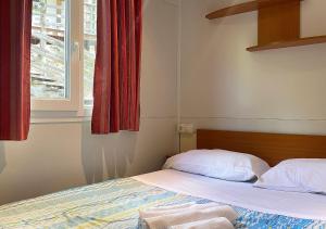 a bedroom with a bed and a window with red curtains at Camping Village la Verna in Chiusi della Verna +69 photos