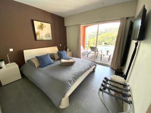 a bedroom with a bed with blue pillows and a balcony at VILLA COLINA in Mandelieu-la-Napoule