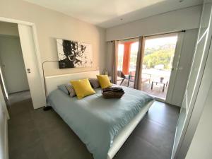 1 dormitorio con 1 cama con almohadas amarillas y balcón en VILLA COLINA, en Mandelieu-la-Napoule