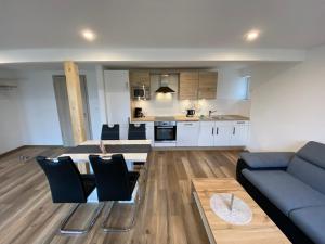 a living room with a blue couch and a kitchen at Pension Pradler Wohnung 3 in Carolinensiel