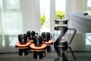 a coffee maker and four coffee cups on a table at Crystal Bay View Apartment in Kalogrea