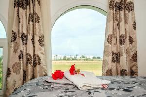 a bed with a pile of towels and red flowers on it at Crystal Bay View Apartment in Kalogrea