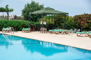 a swimming pool with chairs and a gazebo at Crystal Bay View Apartment in Kalogrea