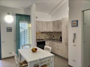 una cucina bianca con tavolo e sedie bianchi di Icaro Residence Apartments with a beautiful pool a SantʼAgata di Militello