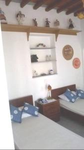 Zimmer mit 2 Betten, einem Tisch und Regalen in der Unterkunft Apartment in the center of Artemonas, Sifnos in Artemonas