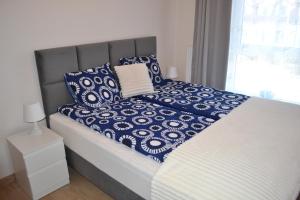 a bed with blue and white sheets and pillows at Apartament Justynka in Kąty Rybackie