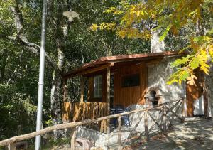 a cabin in the woods with a man sitting in front of it at Camping Village la Verna in Chiusi della Verna