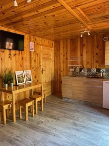 eine Küche mit Holzwänden sowie einem Tisch und Stühlen in der Unterkunft Domek Letniskowy Octopus II in Bobolin