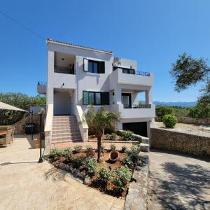 Una casa blanca con escaleras y plantas delante. en Paradisos Villa - Chania, Crete, en Litsárdha