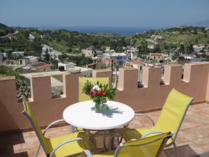 a table and chairs with a vase of flowers on a balcony at Pension Patelo in Pitsidia