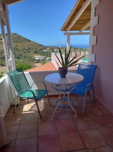 een tafel en stoelen op een balkon met een potplant bij Pension Patelo in Pitsidia