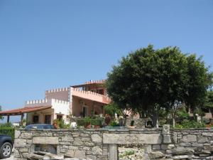 a house behind a stone wall with a tree at Pension Patelo in Pitsidia