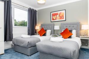 1 dormitorio con 2 camas y 1 silla en Inspiration by Olauda SA - 3 Bed House with Free Parking en Swindon