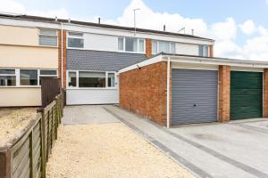 a house with two garage doors and a fence at Inspiration by Olauda SA - 3 Bed House with Free Parking in Swindon