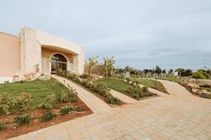 a house with a brick walkway in front of a yard at Agriresort Murciano in Otranto