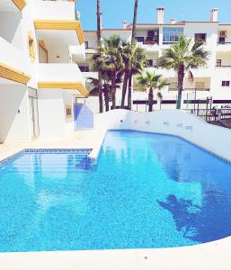 - une piscine en face d'un bâtiment avec des palmiers dans l'établissement Albufeira Central Apartment, 10 mins walk to beach, à Albufeira