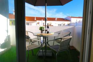 d'une table et de chaises sur un balcon avec un parasol dans l'établissement Albufeira Central Apartment, 10 mins walk to beach, à Albufeira