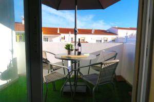 una mesa y sillas en un balcón con sombrilla en Albufeira Central Apartment, 10 mins walk to beach en Albufeira