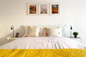 a white bedroom with a bed with a yellow blanket at Albufeira Central Apartment, 10 mins walk to beach in Albufeira
