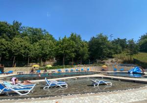 a pool with lounge chairs and people in the water at Camping Village la Verna in Chiusi della Verna
