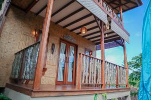 a house with a wooden porch with a balcony at Jepun Didulu Cottages in Candidasa
