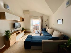 a living room with a blue couch and a tv at Apartment Blue in Sveti Stefan