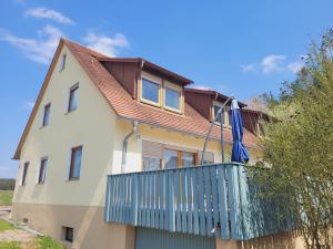 dom z balkonem z niebieskim płotem w obiekcie meinGästehaus im Fränkischen Seenland w mieście Haundorf