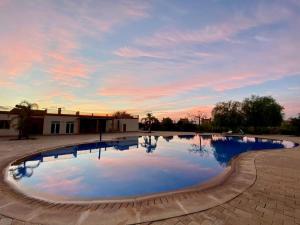 a swimming pool with a sunset in the background at Amizmiz Villa in Marrakesh