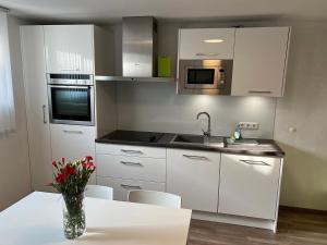 a kitchen with white cabinets and a vase of flowers on a table at FeWo Haus 4 in Lahr