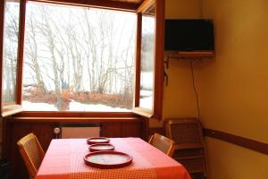 uma mesa num quarto com uma janela e uma televisão em Fiocco di neve, residence Magnola em Ovindoli