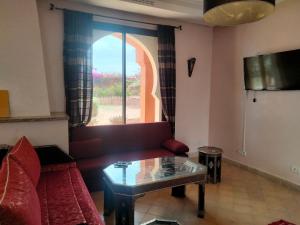 ein Wohnzimmer mit einem roten Sofa und einem Glastisch in der Unterkunft Amizmiz Villa in Marrakesch