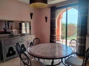 una sala da pranzo con tavolo, sedie e finestra di Amizmiz Villa a Marrakech