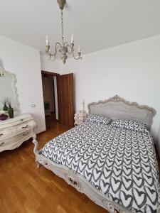 1 dormitorio con cama blanca y lámpara de araña en Casa vacanze Le Rose, en Gabbro